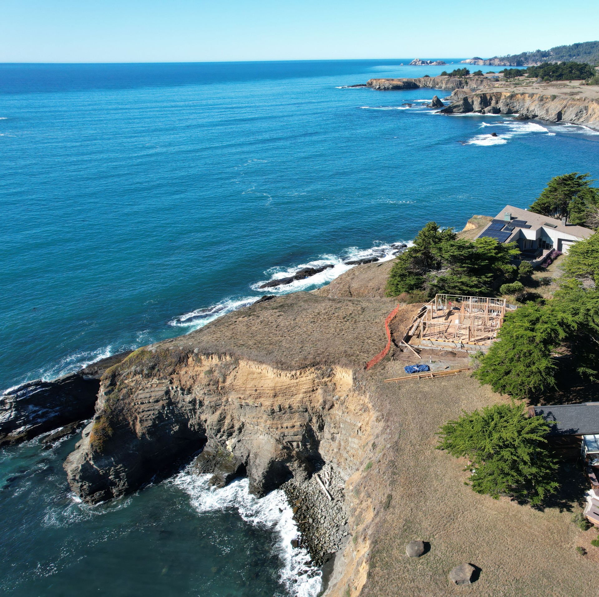 Wood framing of a house under construction by the ocean with aerial drone view.